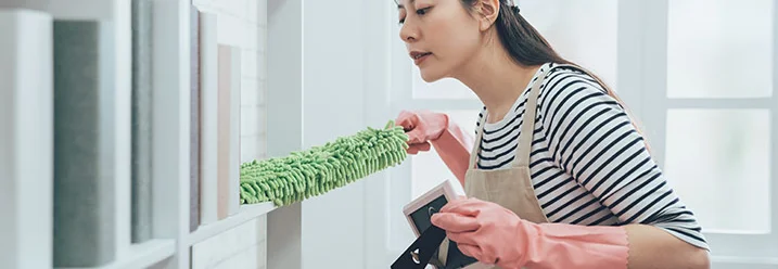 Person entstaubt Regal mit Staubwedel